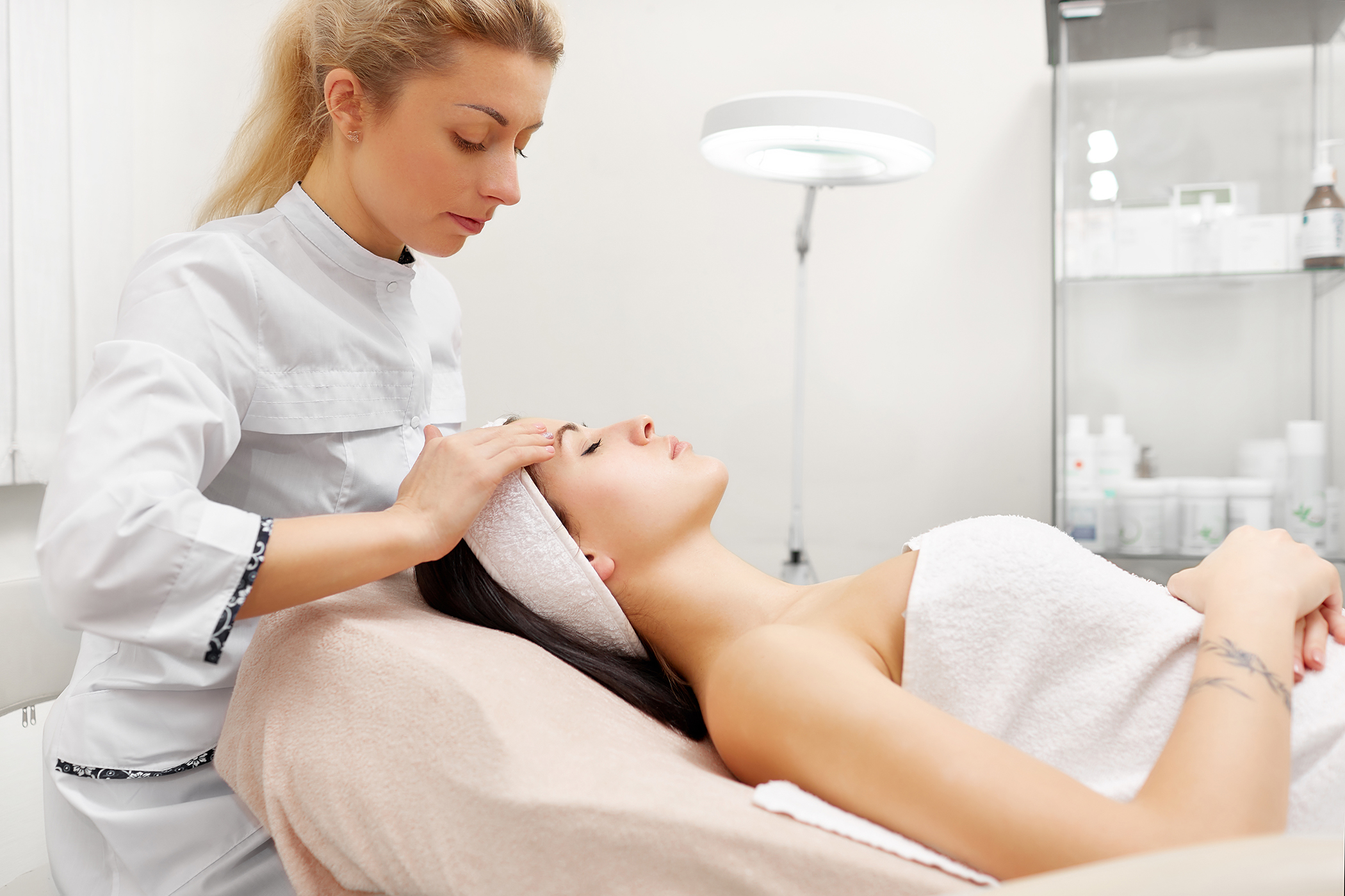 beauty therapist assessing clients skin care in beauty salon