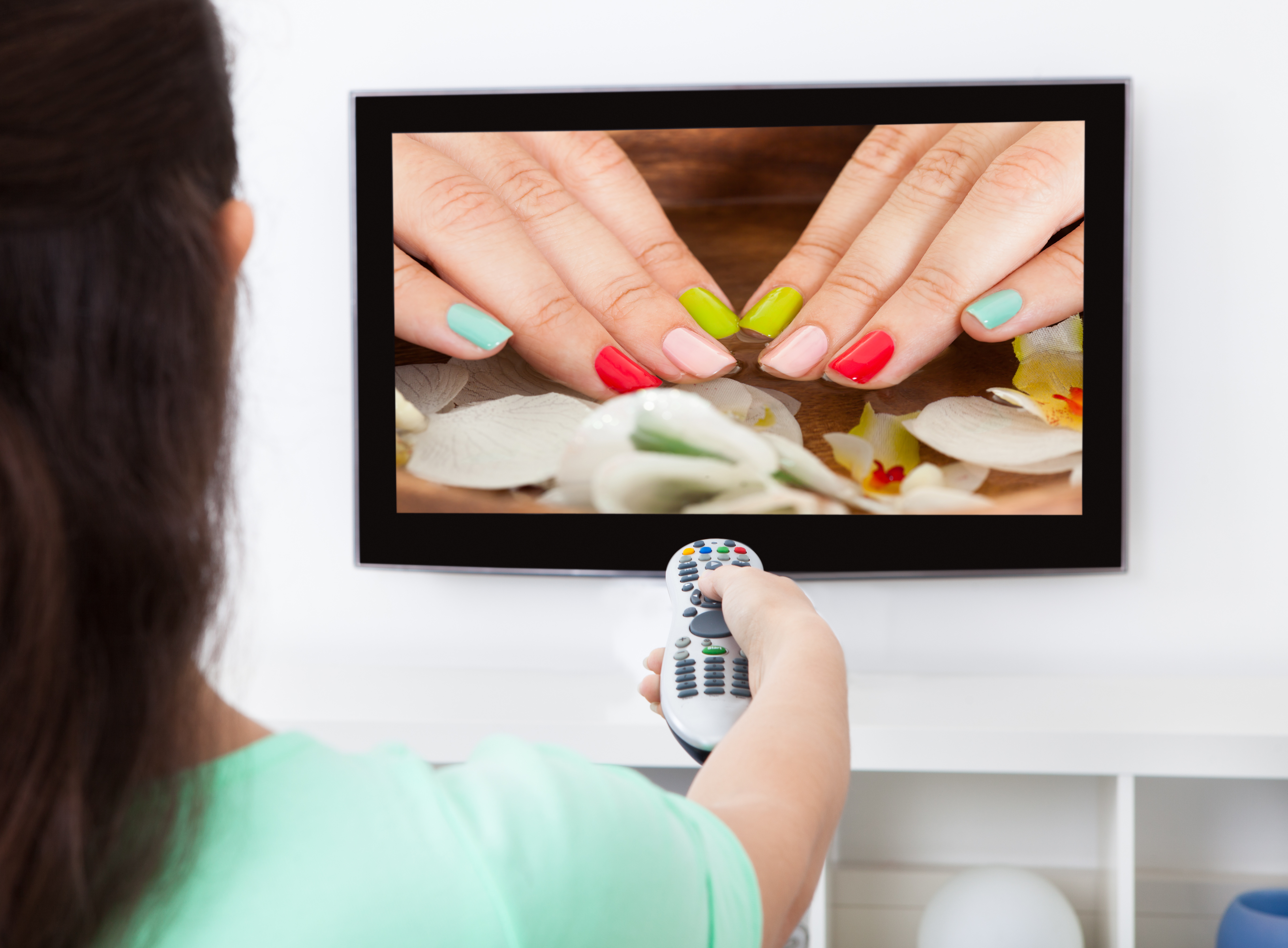 Woman watching nail treatment on TV Screen